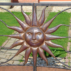 A hand wrought iron gate with the embossed sun - a detail - luxury gates
