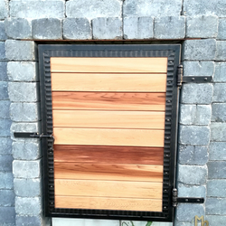 A wrought-iron door as an access to a gas meter combined with cedar wood