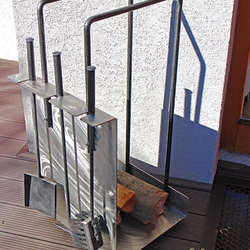A modern stainless steel firewood rack with fireplace tools