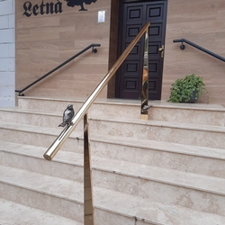 Brass handrail on the stairs at the entrance to the restaurant - a modern railing with a bird